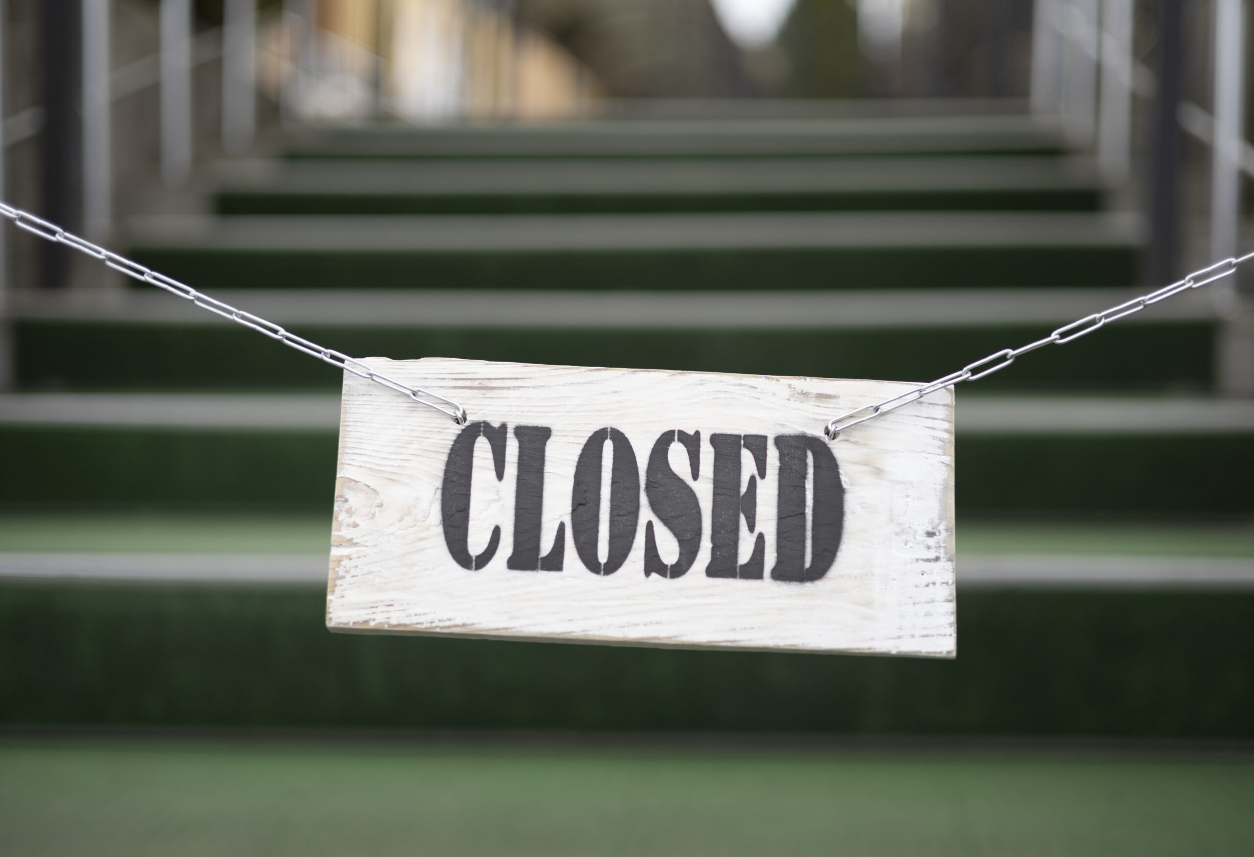 Dřevěná cedule s nápisem CLOSED zavěšená před schody